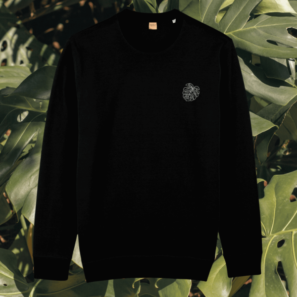 Front view of the Monstera Black organic cotton sweater featuring the “Life’s a Climb but the View is Great” design by Mindful Earth.